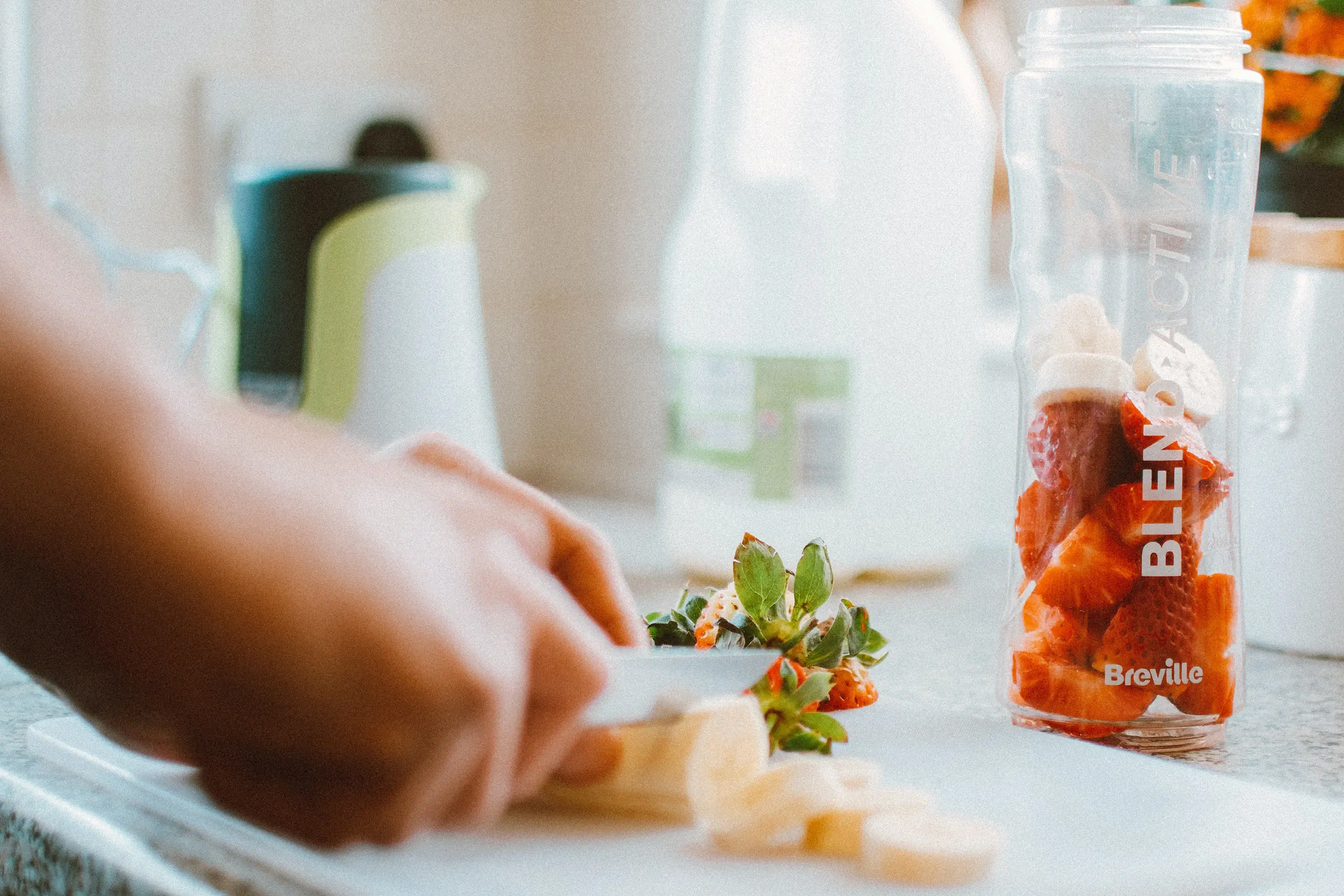 hands cutting fruit for a smoothie